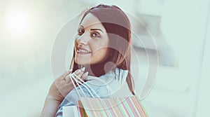 Young woman walking with shopping bags in hand, light effect