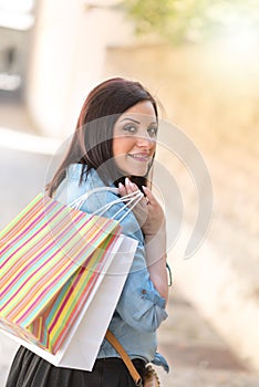 Young woman walking with shopping bags in hand, light effect