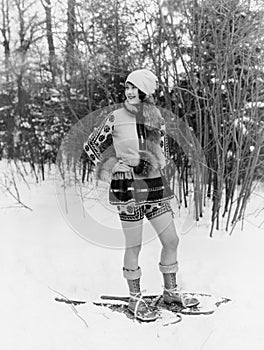 Young woman walking with snow shoes through the woods