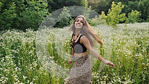 Young woman walking among spring flowers in the meadow