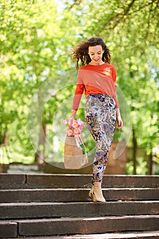 Young woman walking on stairs with shopping bags