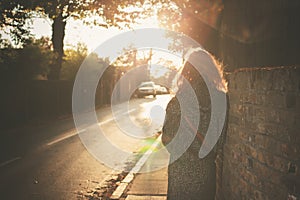 Young woman walking into sunset in city