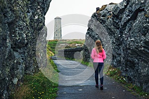 Young woman walking towards Wicklow Head Lighthouse in Ireland