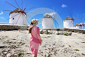 Young woman walking among traditional greek windmills on Mykonos island, Cyclades, Greece