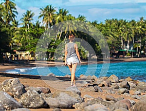 Young woman walking on tropical beach. Summer vacation casual photo