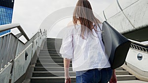Young woman is walking up on stairs on the city street