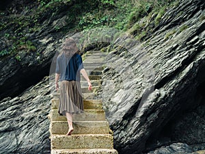 Young woman walking up steps by cliff