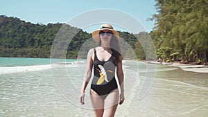 Young woman walks along sandy beach by sea