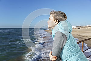 A young woman walks along the sandy seashore in the winter season on a sunny day. Holidays at the resort in the off-season