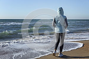 A young woman walks along the sandy seashore in the winter season on a sunny day. Holidays at the resort in the off-season