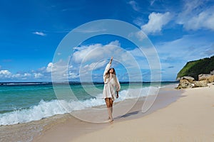 Young woman walks barefoot on the beach