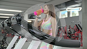 Young woman walks on a cardiovascular machine in the gym
