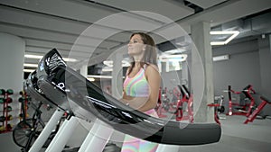 Young woman walks on a cardiovascular machine in the gym