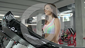 Young woman walks on a cardiovascular machine in the gym