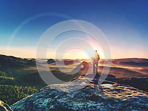 Young woman walks on hill above mist. Strong daybreak sun