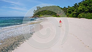 Young woman walks on the sand paradise Anse Bazarca beach. Aerial 4k follow footage view. Ocean waves roll to the shore