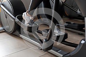 Young woman walks in sportswear on the stepper simulator in the gym. Girl does cardio exercise exercises. Healthy lifestyle.