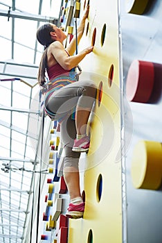 Young woman on the wall in rock-climbing center