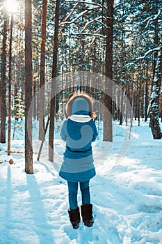 Young woman in warm coat with fur in the winter forest. Winter nature. Selective focus