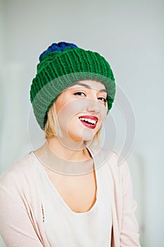 Young woman in warm hand knitted hat at home.