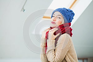 Young woman in warm hand knitted hat at home.