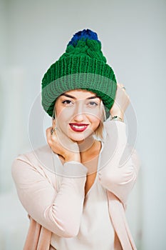 Young woman in warm hand knitted hat at home.