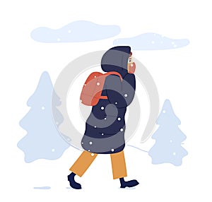 Young woman in warm seasonal outwear walking in winter park. Female character in long down jacket with a backpack