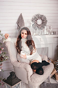 Young woman in a warm sweater, holding a cup and drink hot tea,