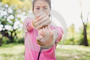 Young woman warm up her body by stretching her arms to be ready for exercising and do yoga in the park.