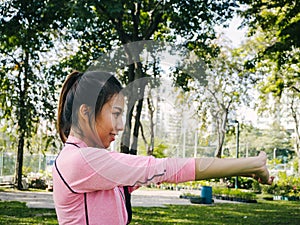 Young woman warm up her body by stretching her arms to be ready for exercising and do yoga in the park.