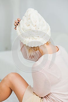 Young woman in warm white hand knitted hat at home