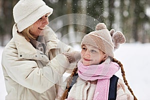 Young woman in warm winterwear playing with her daughter in forest