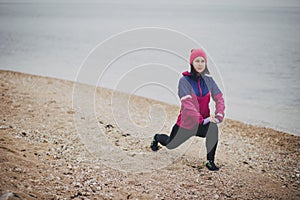 Young woman warming up before jogging at the beach