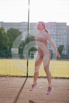 Young woman warming up and jumping up on the sports ground before training