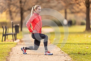 A young woman warms up before jogging and warms up her leg muscles