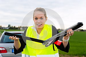 Young woman with warning triangle on street