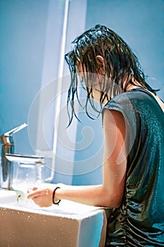 A Young Woman washes her hands in the white sink from the virus Covid-19