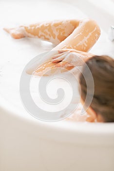 Young woman washing in bathtub. rear view
