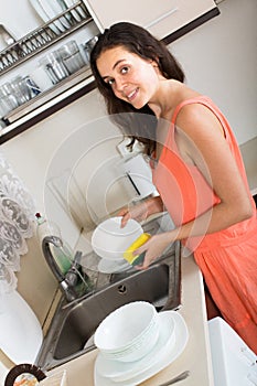 Young woman washing dirty dishes in kitchen