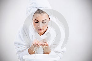 Young woman washing face with clean water.