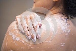 Young woman washing her body with shower gel