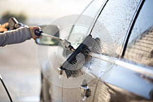 Young woman washing her car in a manual carwash