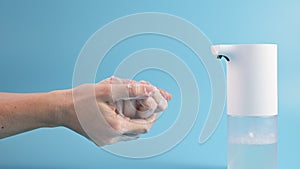 Young woman washing her hands with soapy foam on blue background. Concept of hand washing, hygiene, health, virus and