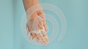 Young woman washing her hands with soapy foam on blue background. Concept of hand washing, hygiene, health, virus and