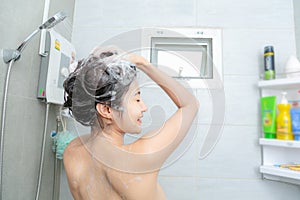 Young woman washing her head in the shower by shampoo
