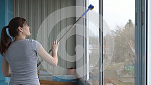 Young woman washing windows with rubber mop