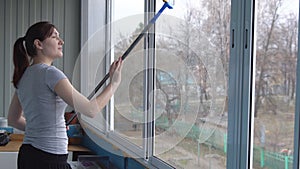 Young woman washing windows with rubber mop