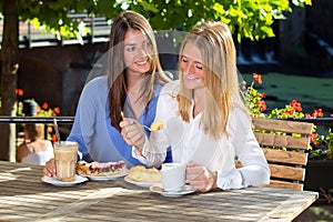 Young woman watching her friend eating cake