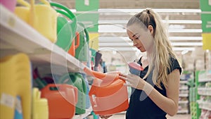 Young woman is watching a plastic watering can for gardening in a store