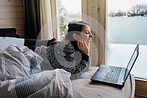 Young woman watching streaming video comedy on her laptop.Watching movies from home on laptop computer.Online video chat.Laughing,